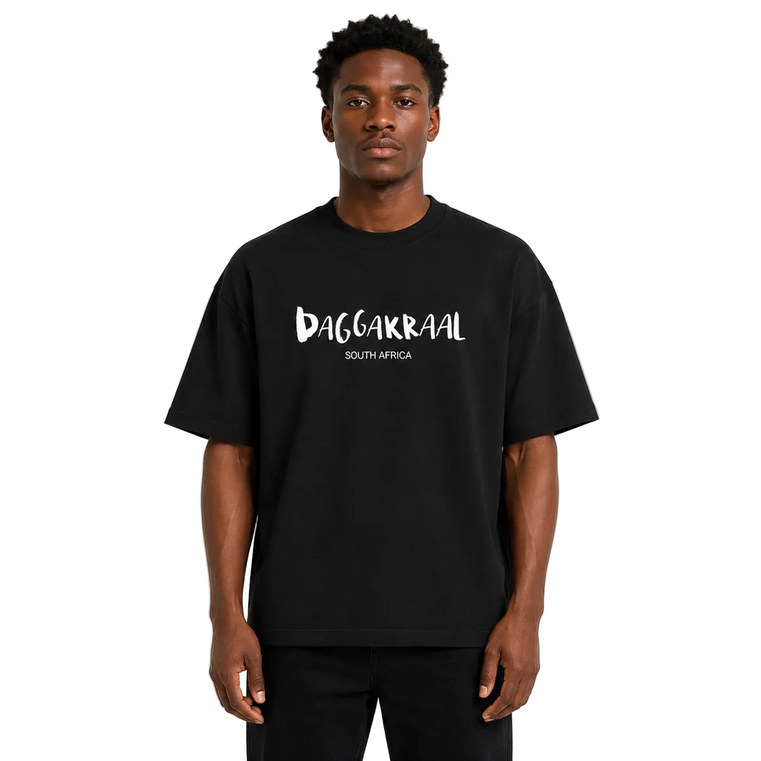 A man wearing a black oversized t-shirt with 'DAGGAKRAAL SOUTH AFRICA' printed in white across the chest, standing against a light gray background.